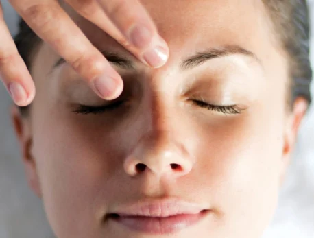 Woman enjoying a relaxing facial massage at spa resort, eyes closed in serene comfort.