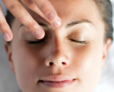Woman enjoying a relaxing facial massage at spa resort, eyes closed in serene comfort.