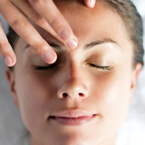 Woman enjoying a relaxing facial massage at spa resort, eyes closed in serene comfort.