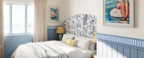 Cosy hotel room with blue accents and seaside-themed artwork.
