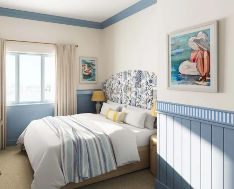 Cosy hotel room with blue accents and seaside-themed artwork.