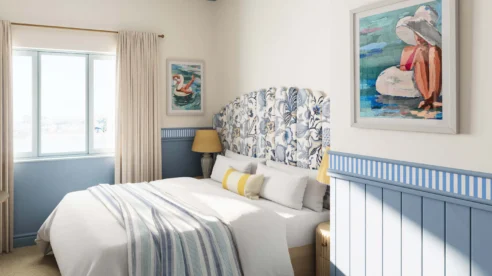 Cosy hotel room with blue accents and seaside-themed artwork.
