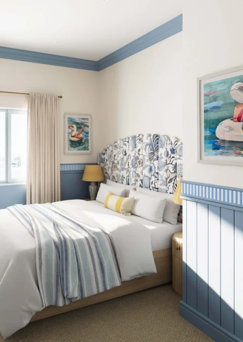 Cosy hotel room with blue accents and seaside-themed artwork.
