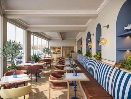 Elegant restaurant with harbour views, featuring blue-striped seating and warm wooden accents.