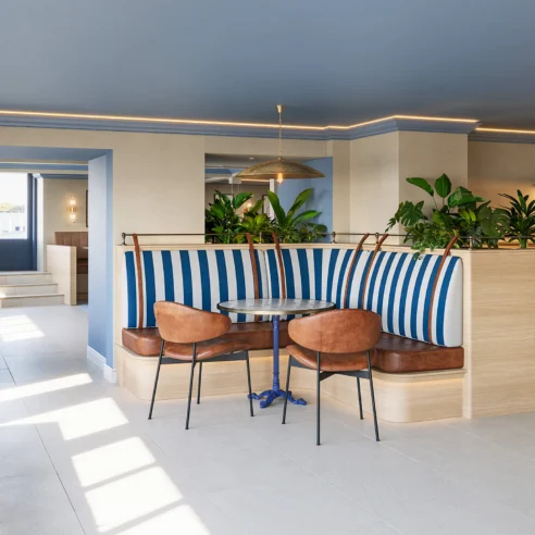 Family enjoying a cosy, sunlit hotel lounge with blue accents and comfortable seating.