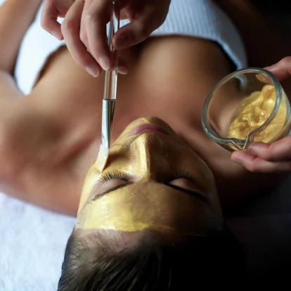 Luxurious spa treatment with a gold facial mask application, promoting relaxation.