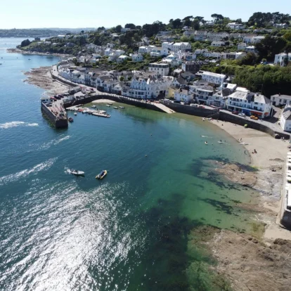 Aerial view of families enjoying a sunny day by the seaside, in a picturesque coastal village.