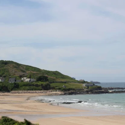 Scenic coastal view with sandy beach and green hills, ideal for family relaxation.
