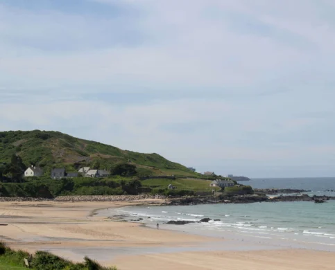 Scenic coastal view with sandy beach and green hills, ideal for family relaxation.