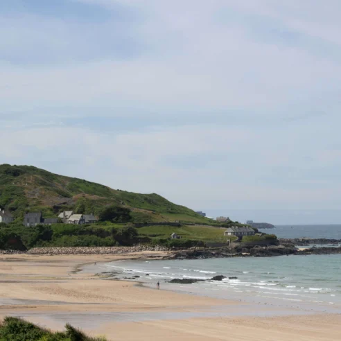 Scenic coastal view with sandy beach and green hills, ideal for family relaxation.