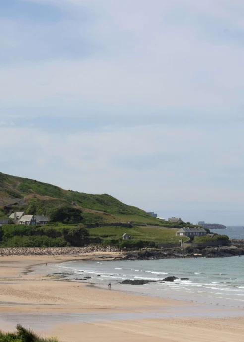 Scenic coastal view with sandy beach and green hills, ideal for family relaxation.