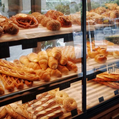A bakery display with assorted fresh pastries and breads in a cosy hotel cafe.