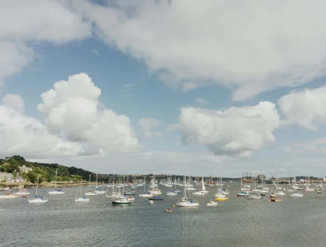 Group sailing near a picturesque harbour on a cloudy day.