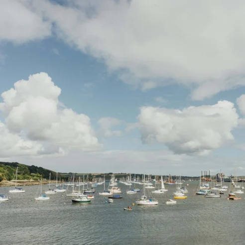 Group sailing near a picturesque harbour on a cloudy day.
