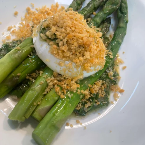 Fresh asparagus with poached egg and crispy breadcrumbs in elegant resort dining.