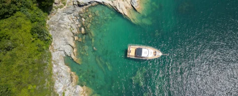 Family enjoying a luxurious boat ride on clear turquoise waters near a rocky coastline.