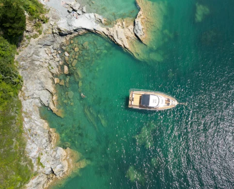 Family enjoying a luxurious boat ride on clear turquoise waters near a rocky coastline.