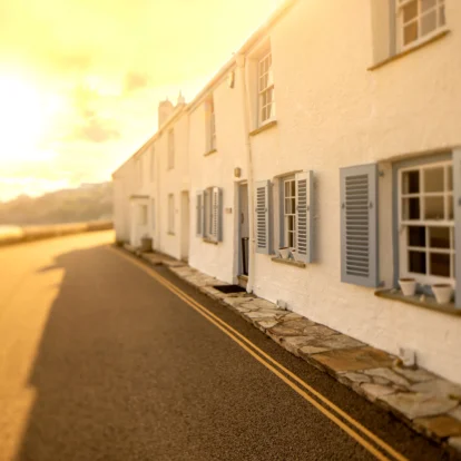 Cosy cottages with blue shutters bathed in warm sunset light, perfect for a family retreat.