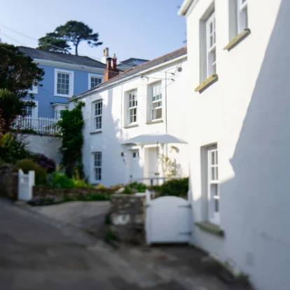 Charming white cottages along a peaceful, sunlit alley in a seaside village.
