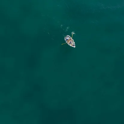 Aerial view of a family in a small boat on calm, turquoise sea, enjoying a sunny day.