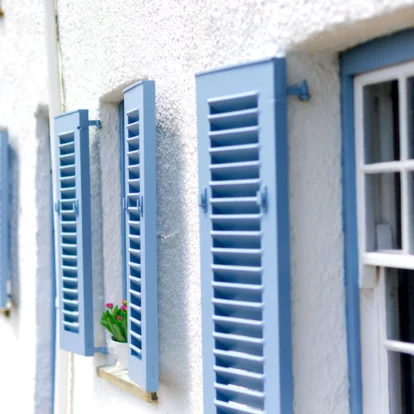 Blue shutters on white hotel wall with small flower pot in window