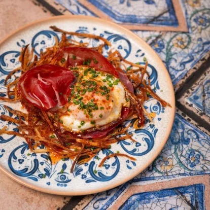 Elegant brunch plate with crispy potato nest, cured ham and soft egg, warm hotel dining