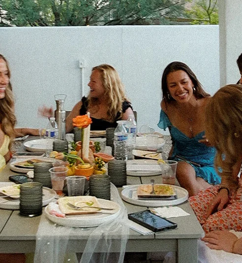 A family enjoying a joyful meal together outdoors, surrounded by nature and a beautifully set table.