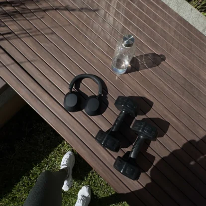 Family enjoying outdoor workout area — sneakers, dumbbells, headphones and bottle on deck
