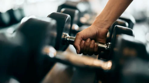 Family member lifting a dumbbell in a hotel gym, close-up of hand gripping weight, inviting wellness facilities